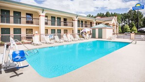 Zona de piscina con sillas de descanso y una silla para salvavidas en un Days Inn & Suites.