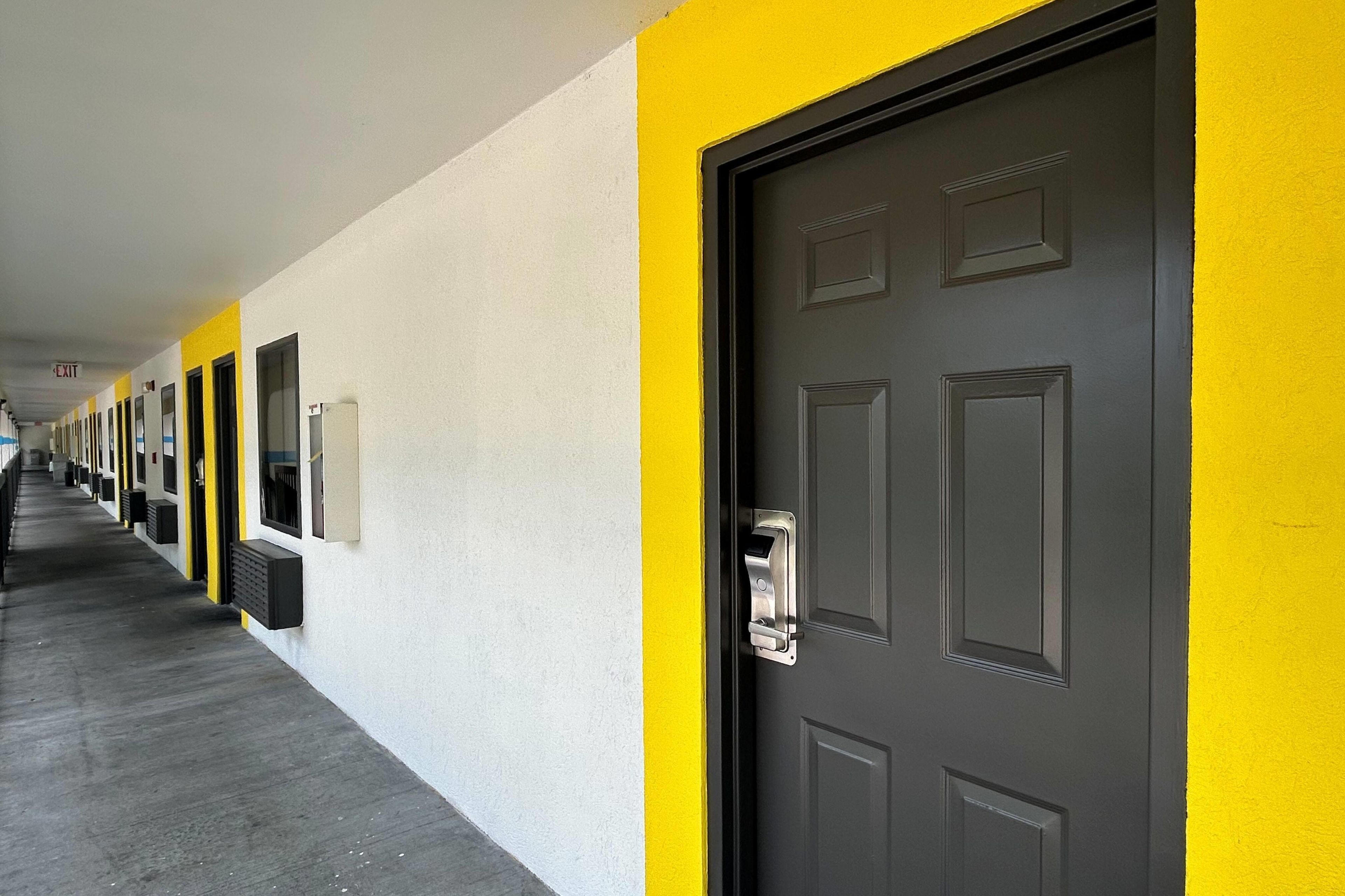 A hallway with doors, each with a window and a door handle.