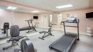 Un gimnasio con equipo de ejercicio, cinta de correr y pared con espejo.