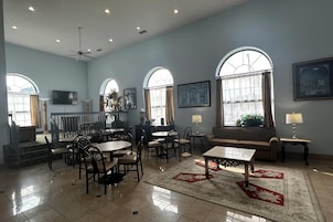 Una habitación amplia con comedor, disposición de asientos y grandes ventanales.