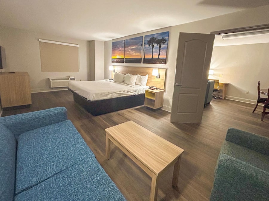 Ein Hotelzimmer mit Bett, Schreibtisch, Sessel, Sofa und einem Gemälde an der Wand.