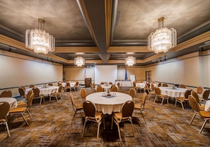 Un salón de conferencias con mesas redondas, sillas y candelabros.