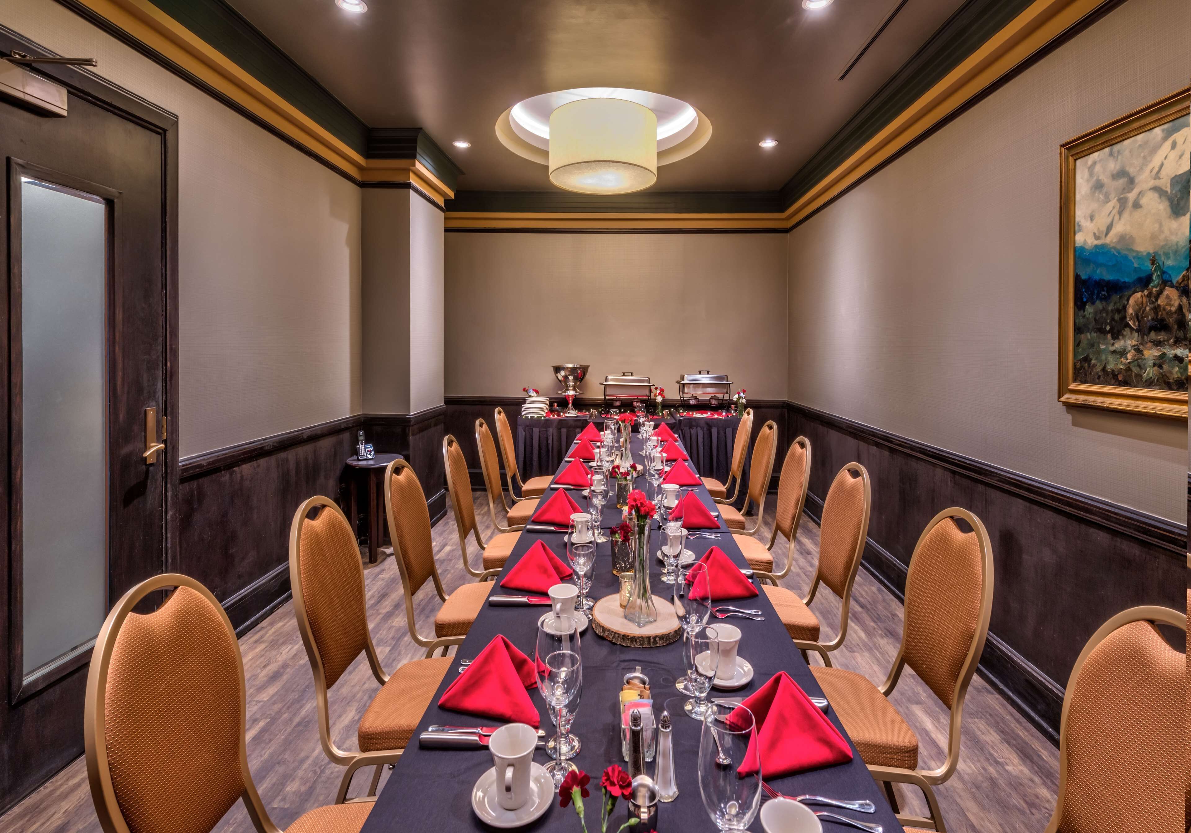 A long conference table set for a formal event, with chairs and red napkins.