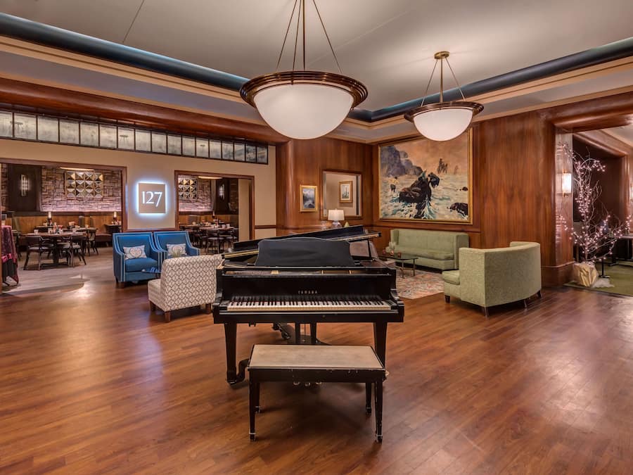 Un hall d’entrée spacieux, agrémenté d’un grand piano, de sièges confortables et d’un grand panneau indiquant le numéro « 127 ».