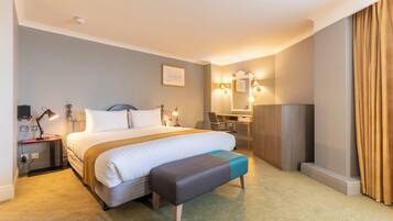 Une chambre d’hôtel avec un grand lit, des tables de chevet, un bureau et une chaise.