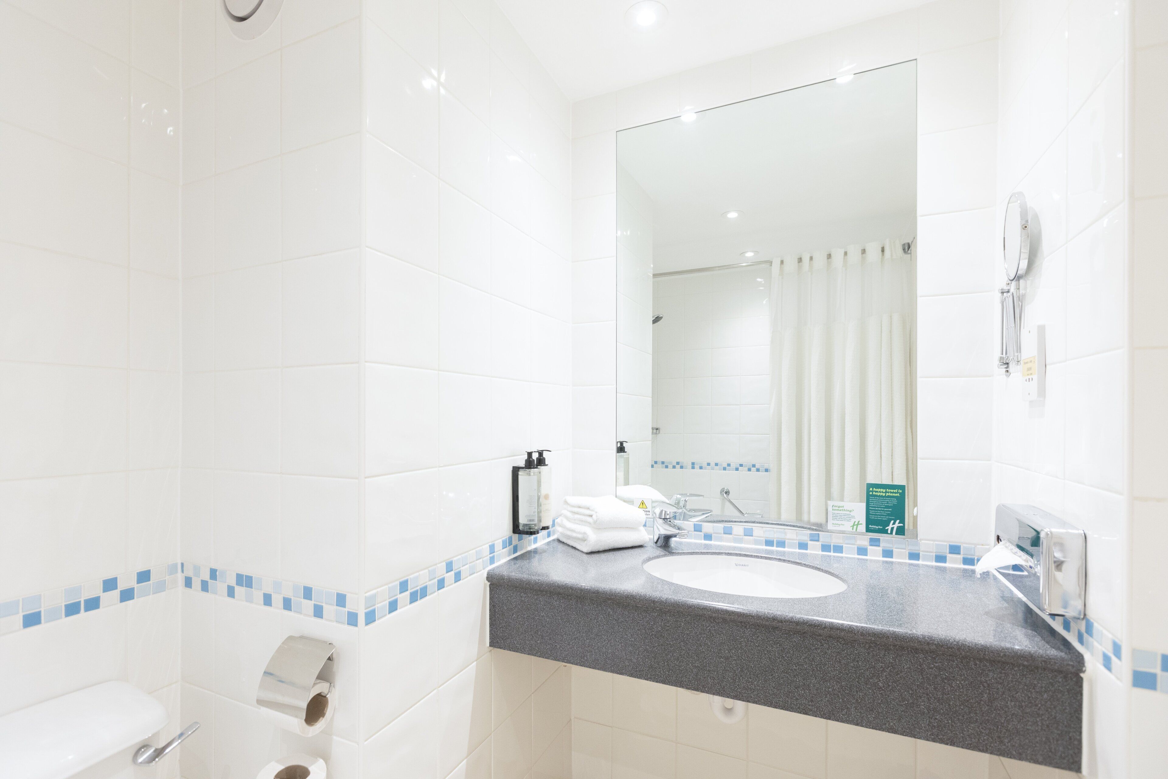 A bathroom with a white sink, a mirror, and a shower.