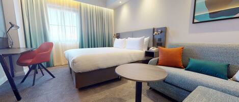 Una habitación de hotel con cama, sofá, escritorio y silla.