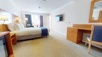 A hotel room with a bed, desk, chair, and a television on the wall.