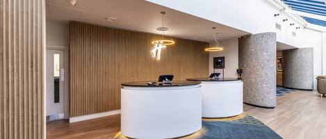 A modern reception area with two reception desks, wooden slat walls, and a skylight.