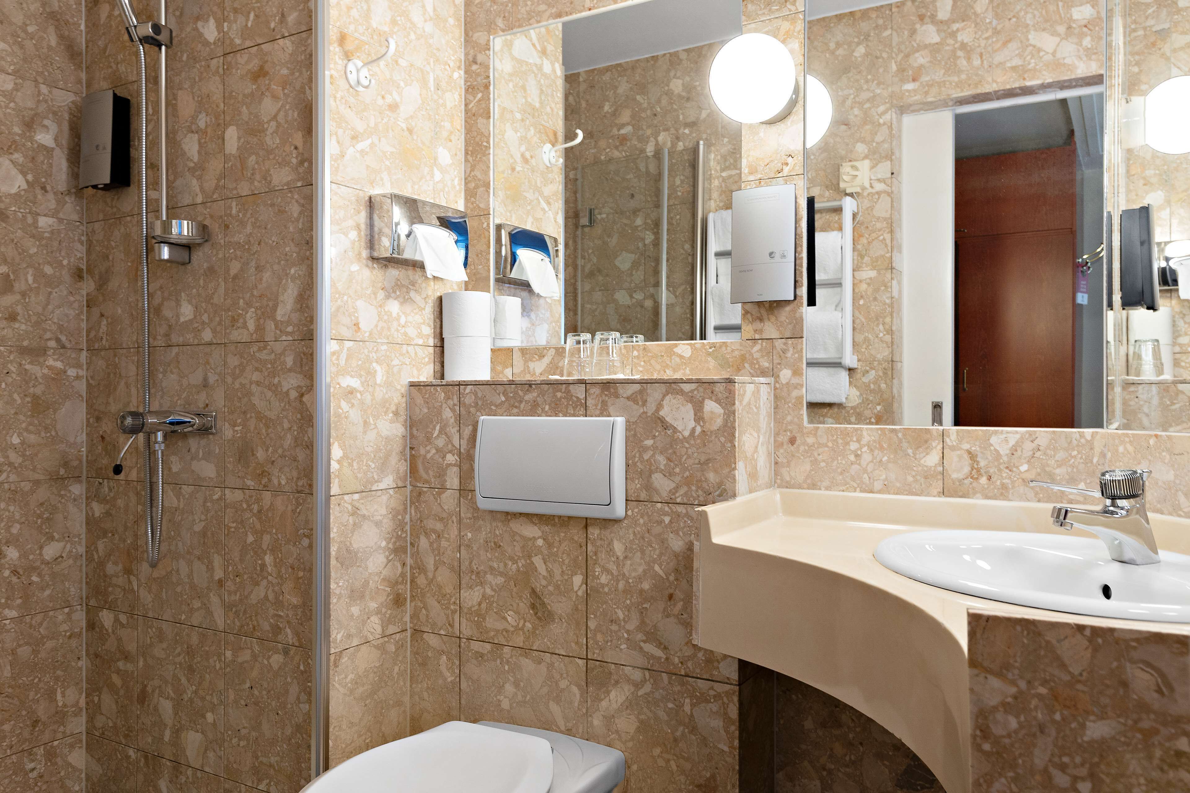 A modern bathroom with a shower, sink, and toilet.
