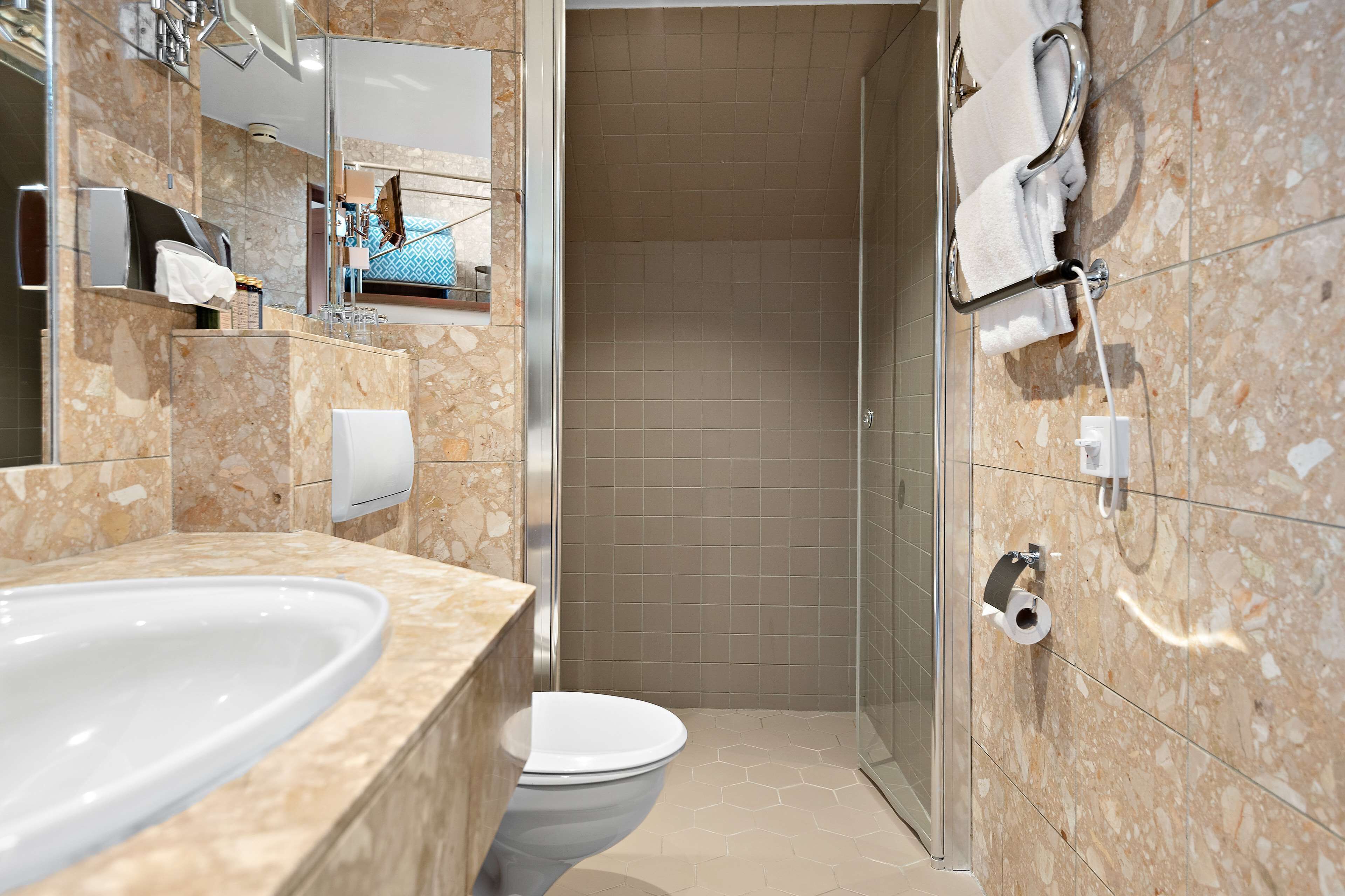 A modern bathroom with a marble sink, toilet, and shower.