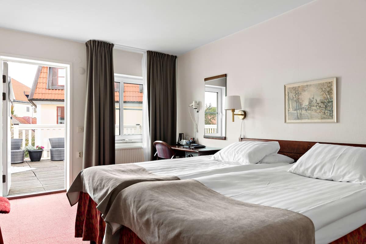 Une chambre d’hôtel avec un grand lit, un bureau, une chaise et une vue sur l’extérieur.