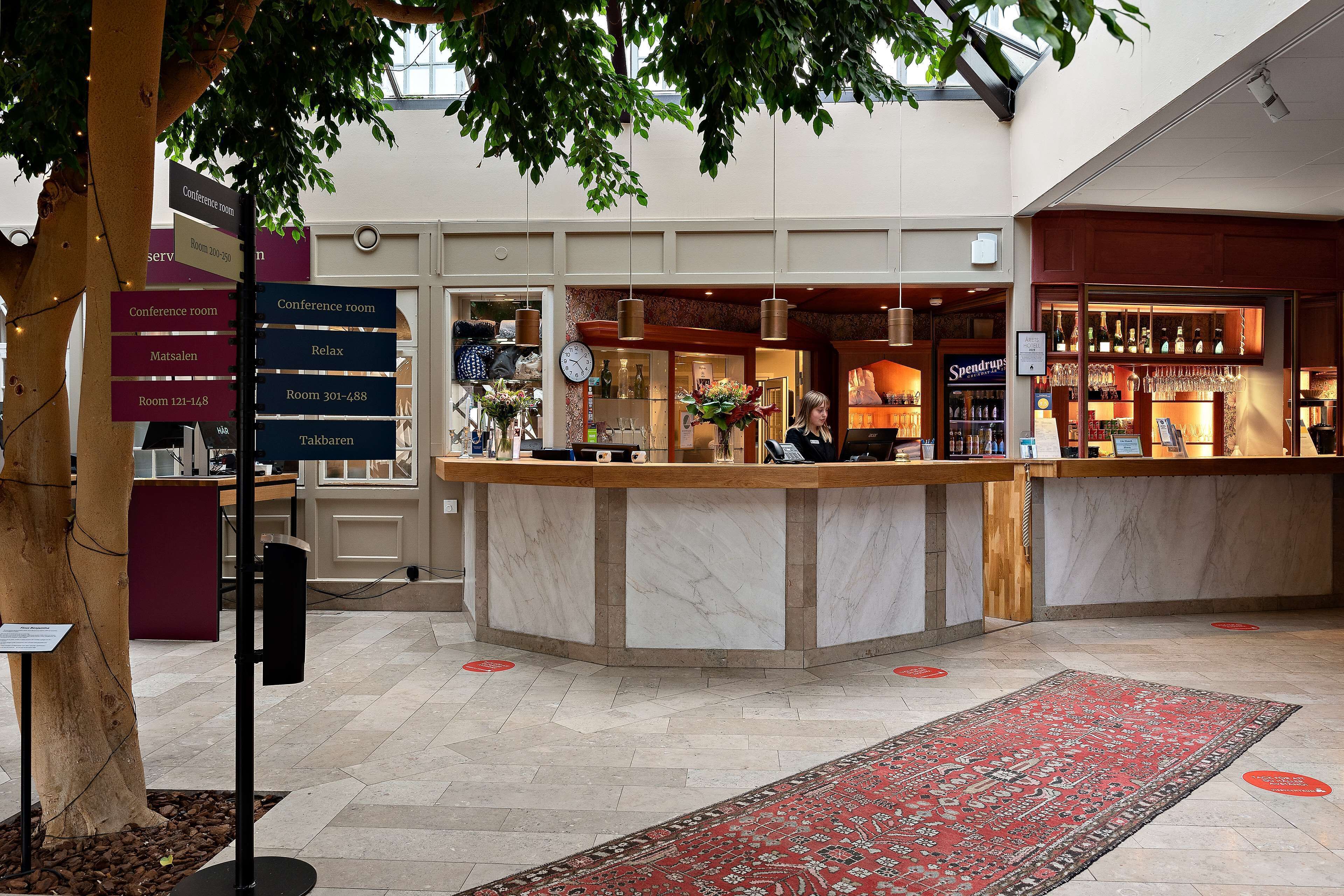A hotel lobby with a reception desk, a bar area, and a conference room sign.