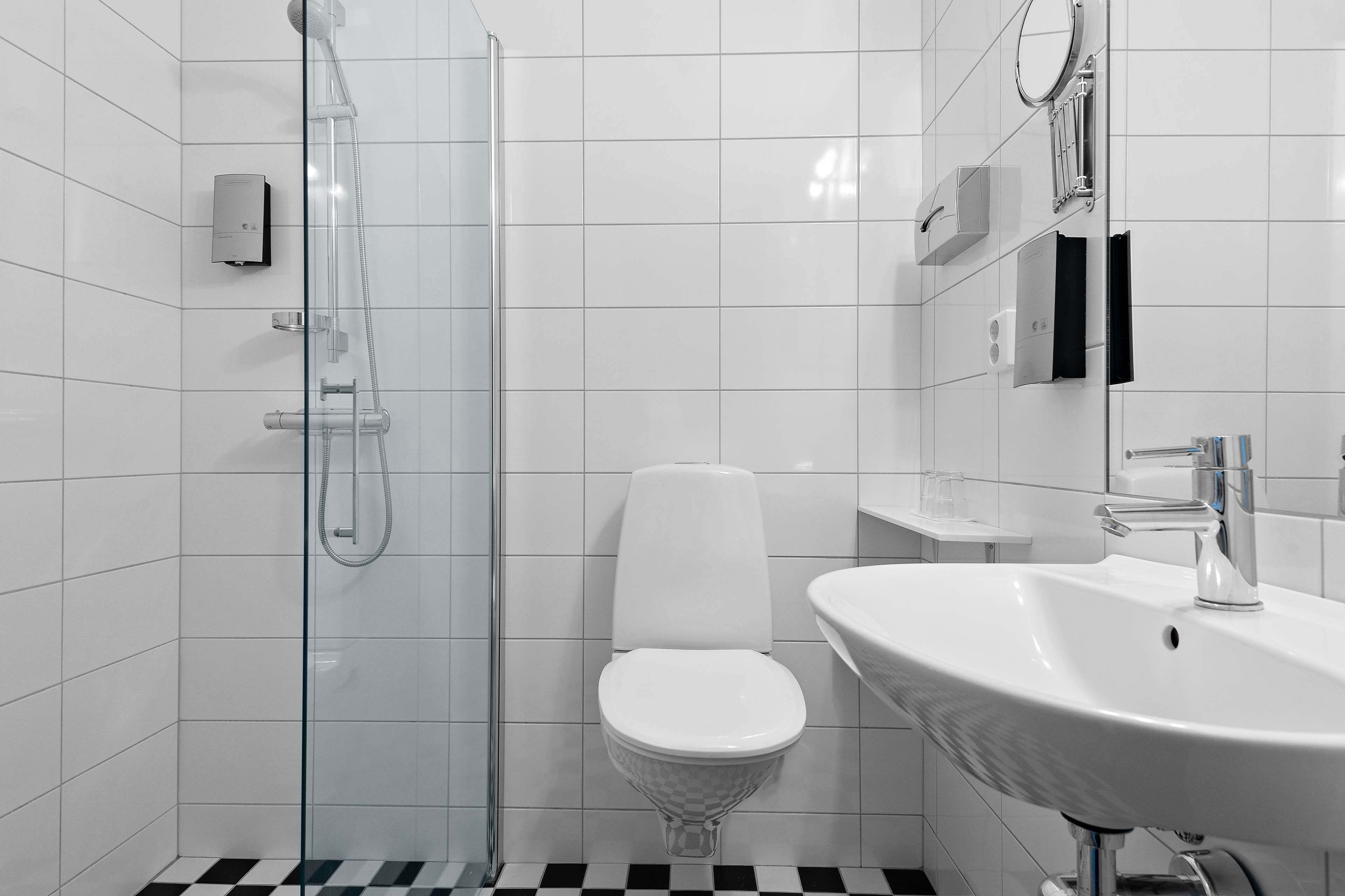 Een moderne badkamer met een douchecabine van glas, een wit toilet en een wastafel met spiegel.