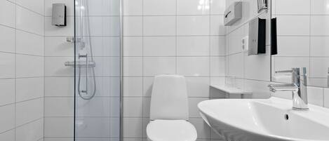 Een moderne badkamer met een douchecabine van glas, een wit toilet en een wastafel met spiegel.