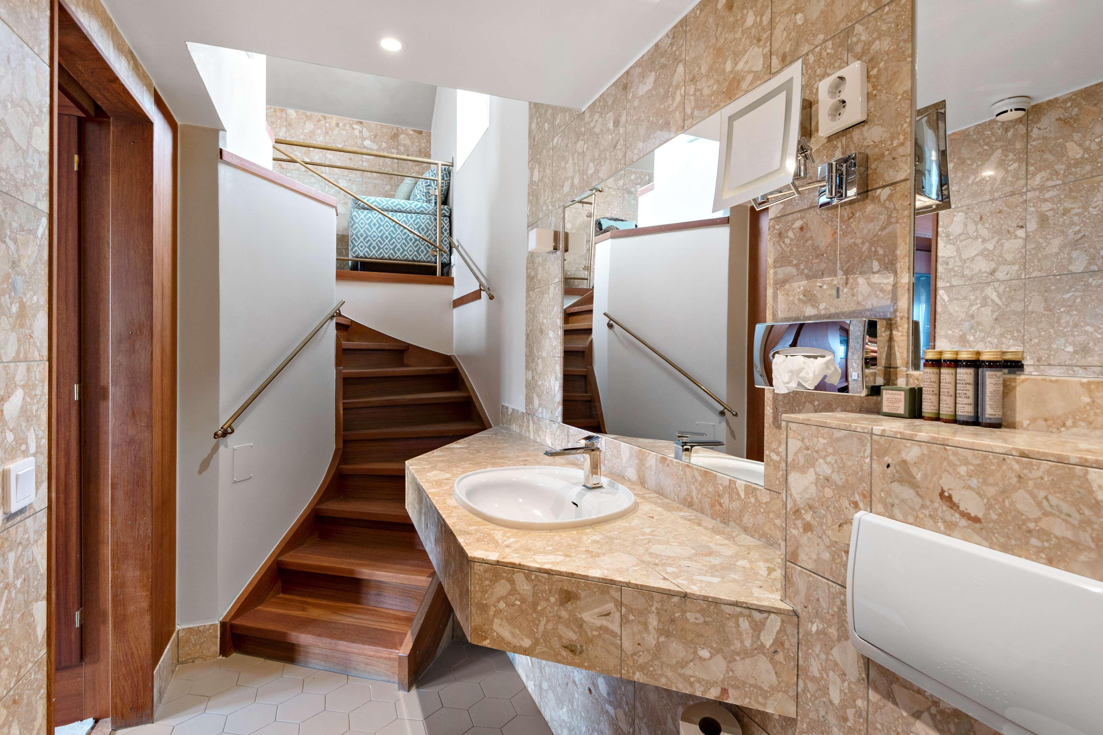 A modern bathroom with a marble vanity, a large mirror, and a built-in toilet.