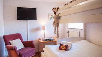 Cozy retreat with a bunk bed, mounted TV, plush armchair, and a bedside table.
