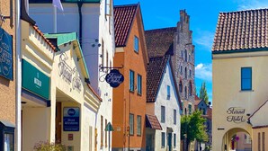Une rue pavée bordée de bâtiments historiques, dont un hôtel sur lequel on peut lire l’inscription « Strand Hotel ».