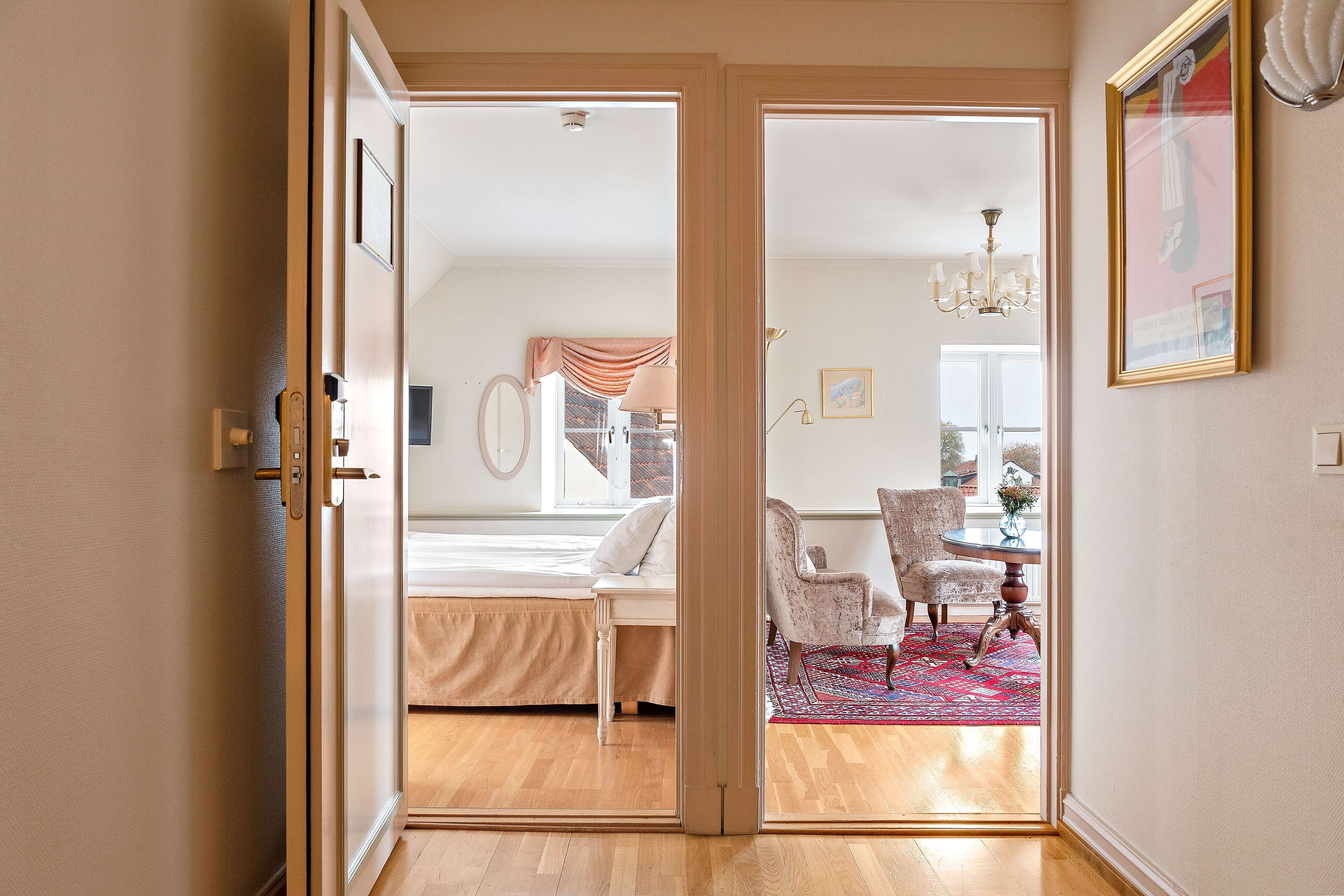 A bedroom with a bed, a chair, a table, and a view of the outdoors.