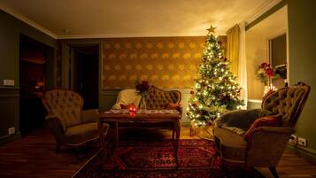 Una sala de estar acogedora con un árbol de Navidad, dos sillones, una mesa de centro y una alfombra estampada.