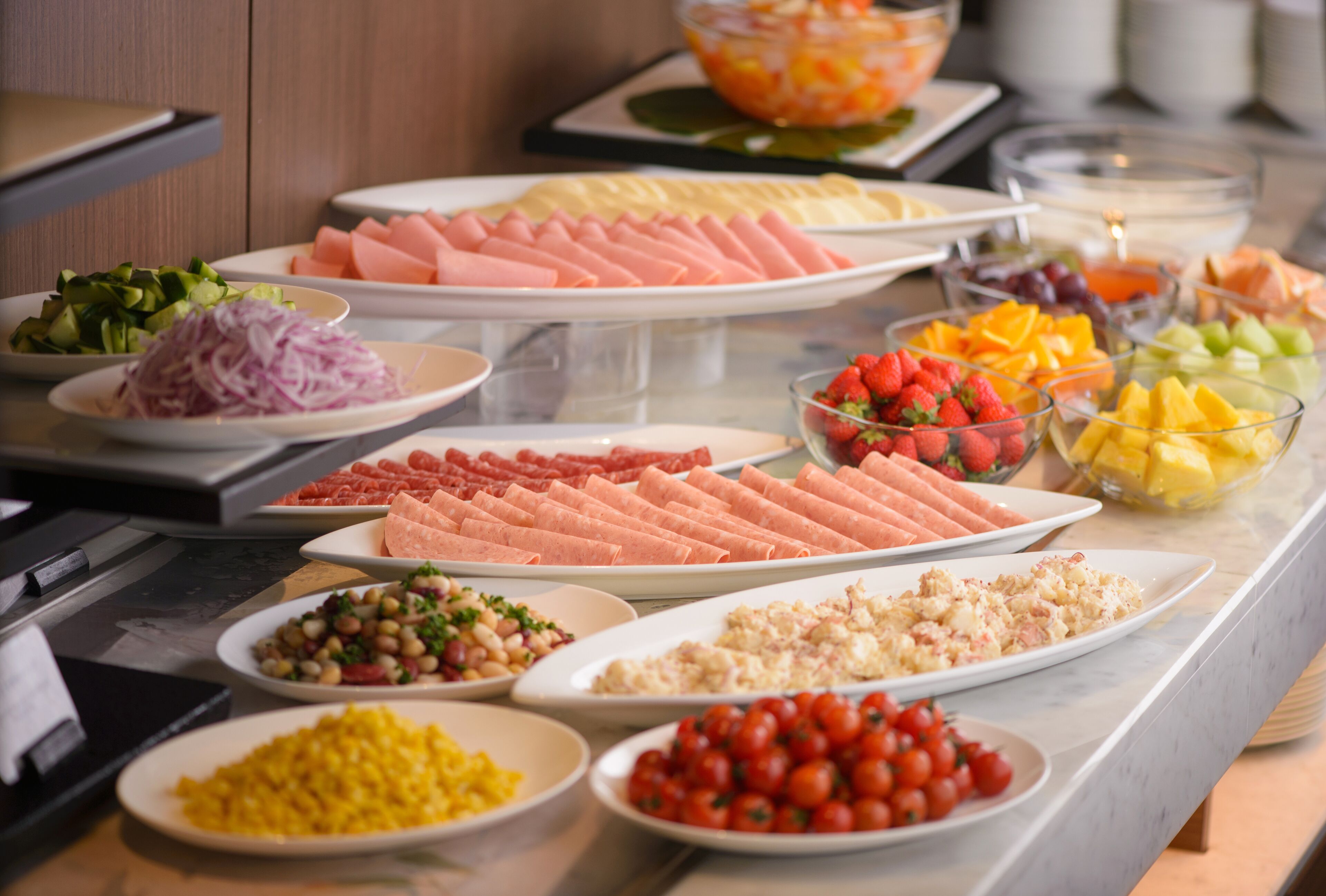 A buffet with various food items including meats, fruits, and vegetables.