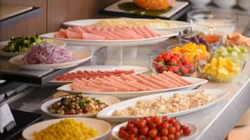 Ein Buffet mit verschiedenen Speisen, darunter Fleisch, Obst und Gemüse.