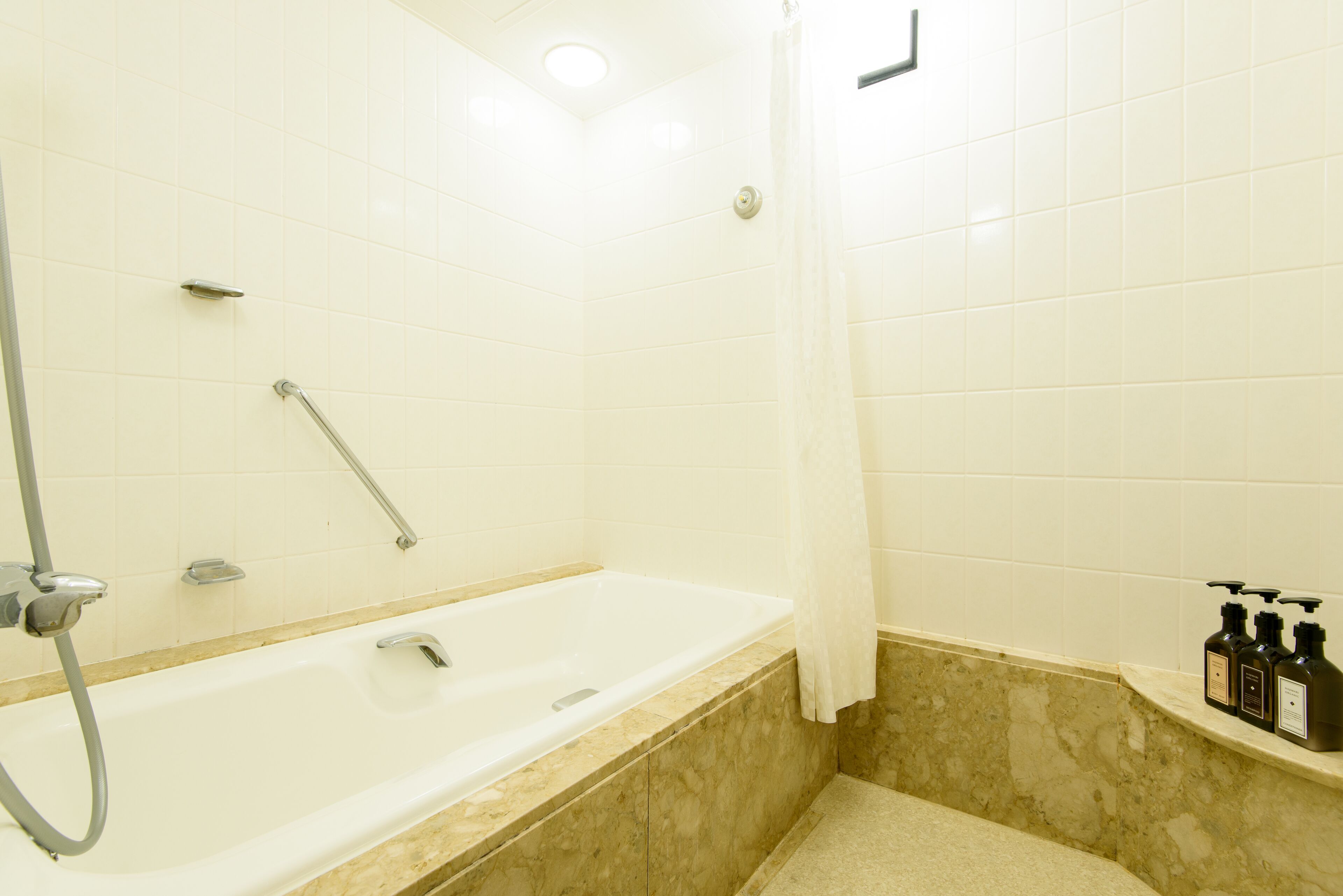 Une salle de bain équipée d’une baignoire, d’une douche et d’une étagère où sont rangés les produits de toilette.