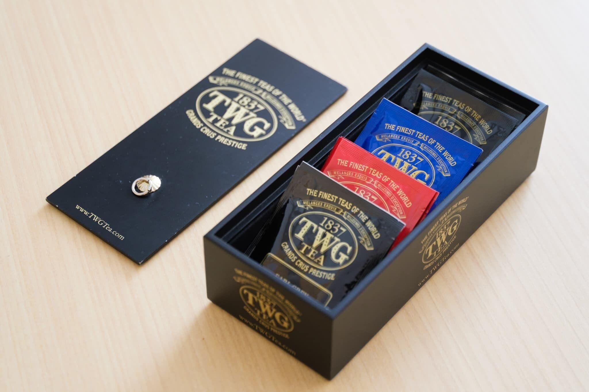 Een zwarte doos met de aanduiding 'TWG TEA' en een website-adres 'www.TWGTea.com'.