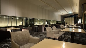 A modern hotel lobby with seating areas, tables, and a decorative wall with plants.