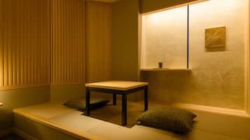 A room with a low wooden bench, a small table, and cushions.