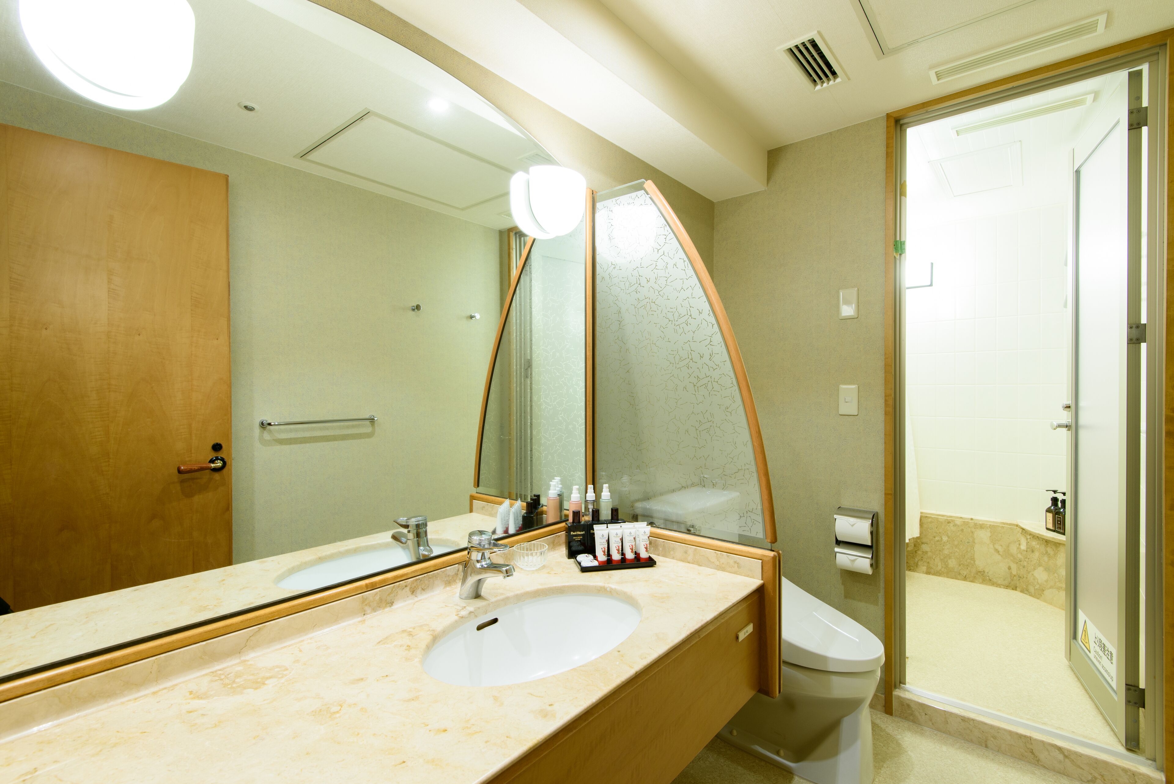 A hotel bathroom with a large sink, mirror, and shower.