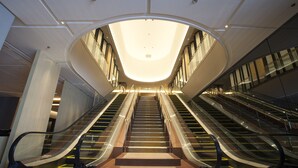A modern interior with two escalators leading to a central area.