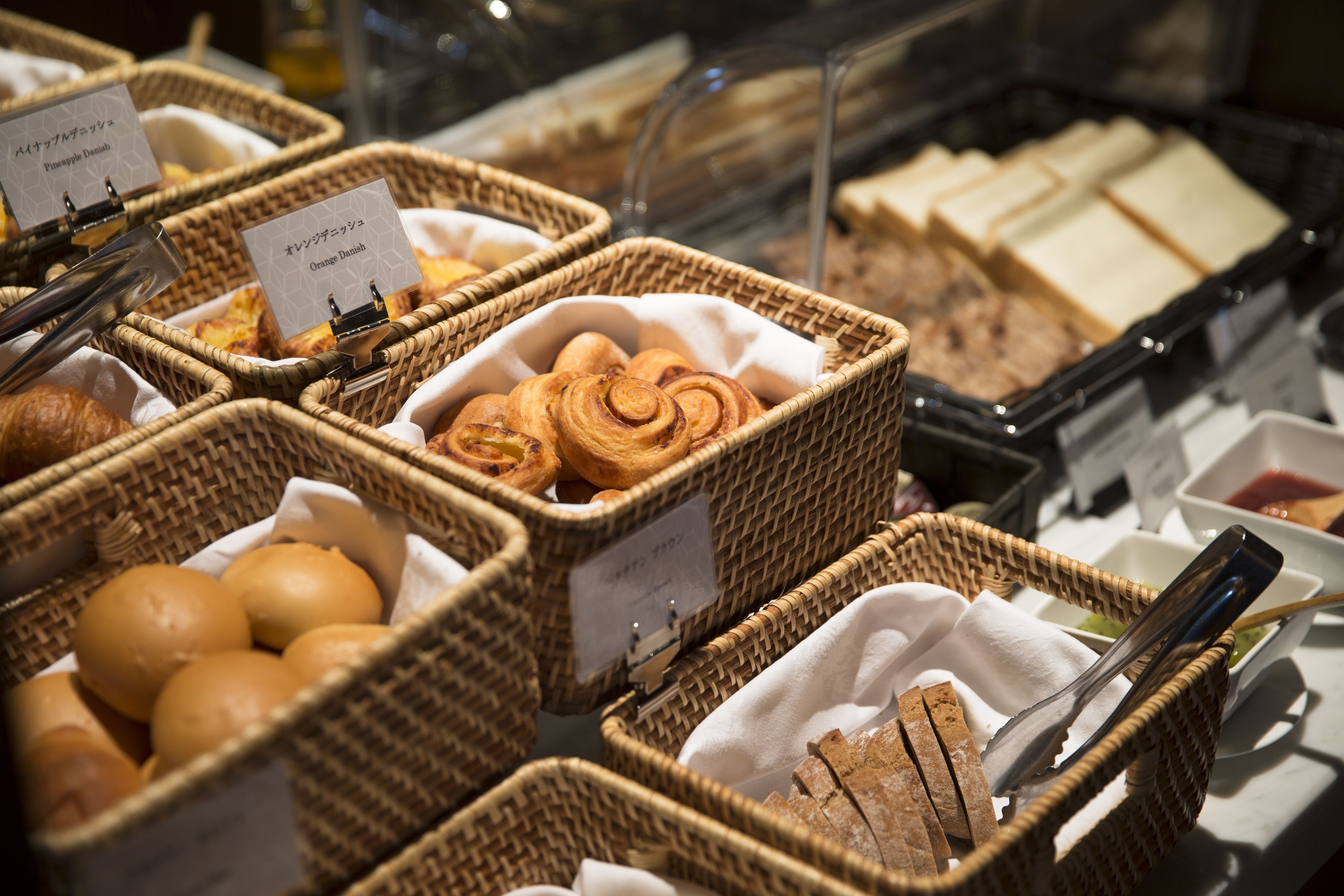 Un buffet de petit-déjeuner proposant une variété de pains et de viennoiseries présentés dans des paniers en osier.
