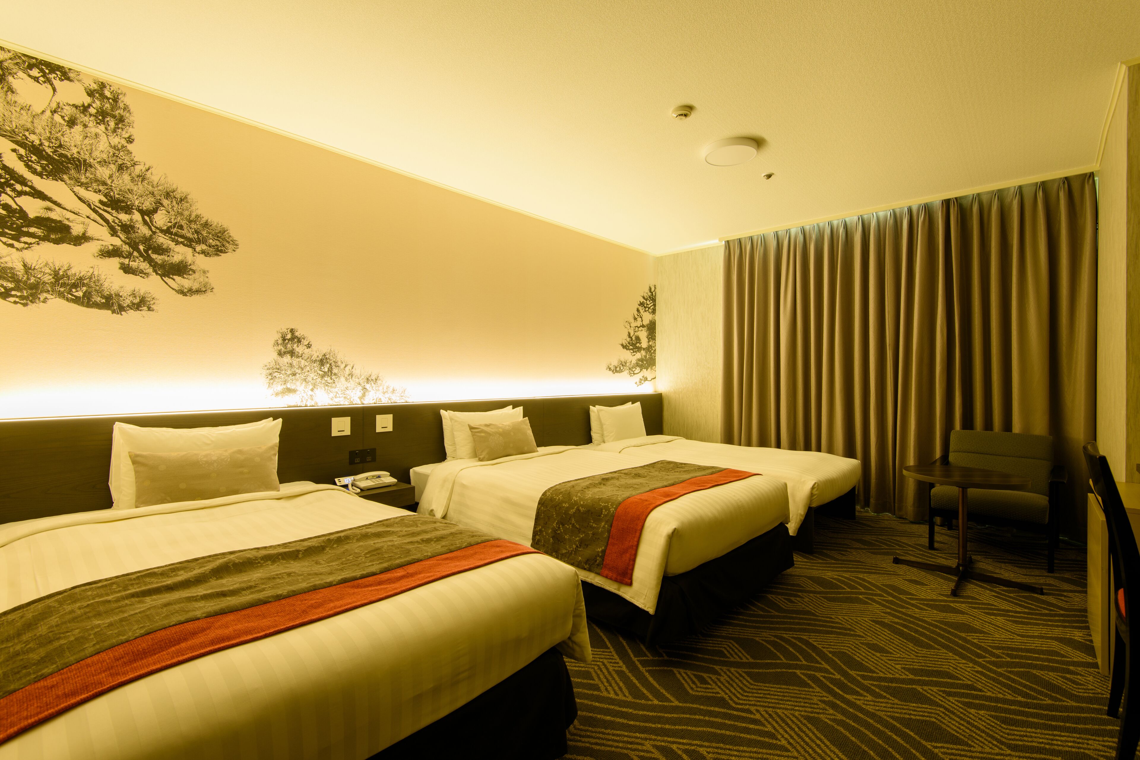 A hotel room with two beds, a desk, and a chair.