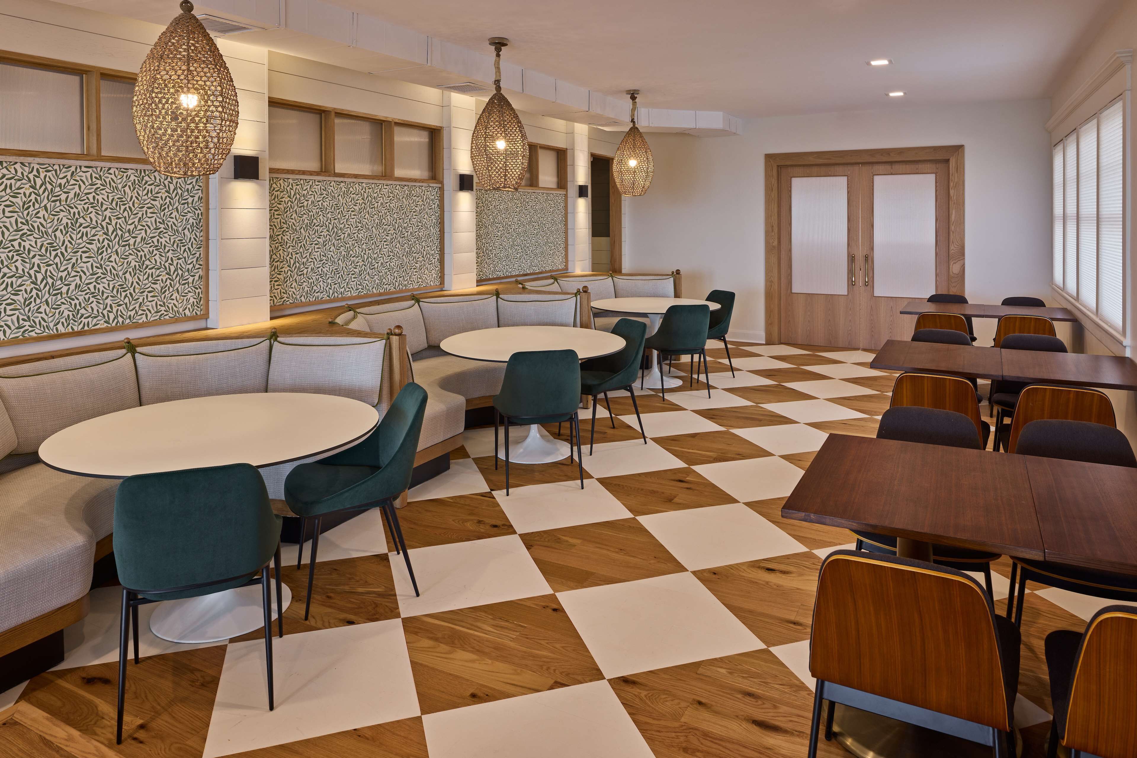 A modern dining area with round tables and chairs, patterned wall panels, and wooden flooring.