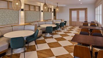 A modern dining area with round tables and chairs, patterned wall panels, and wooden flooring.
