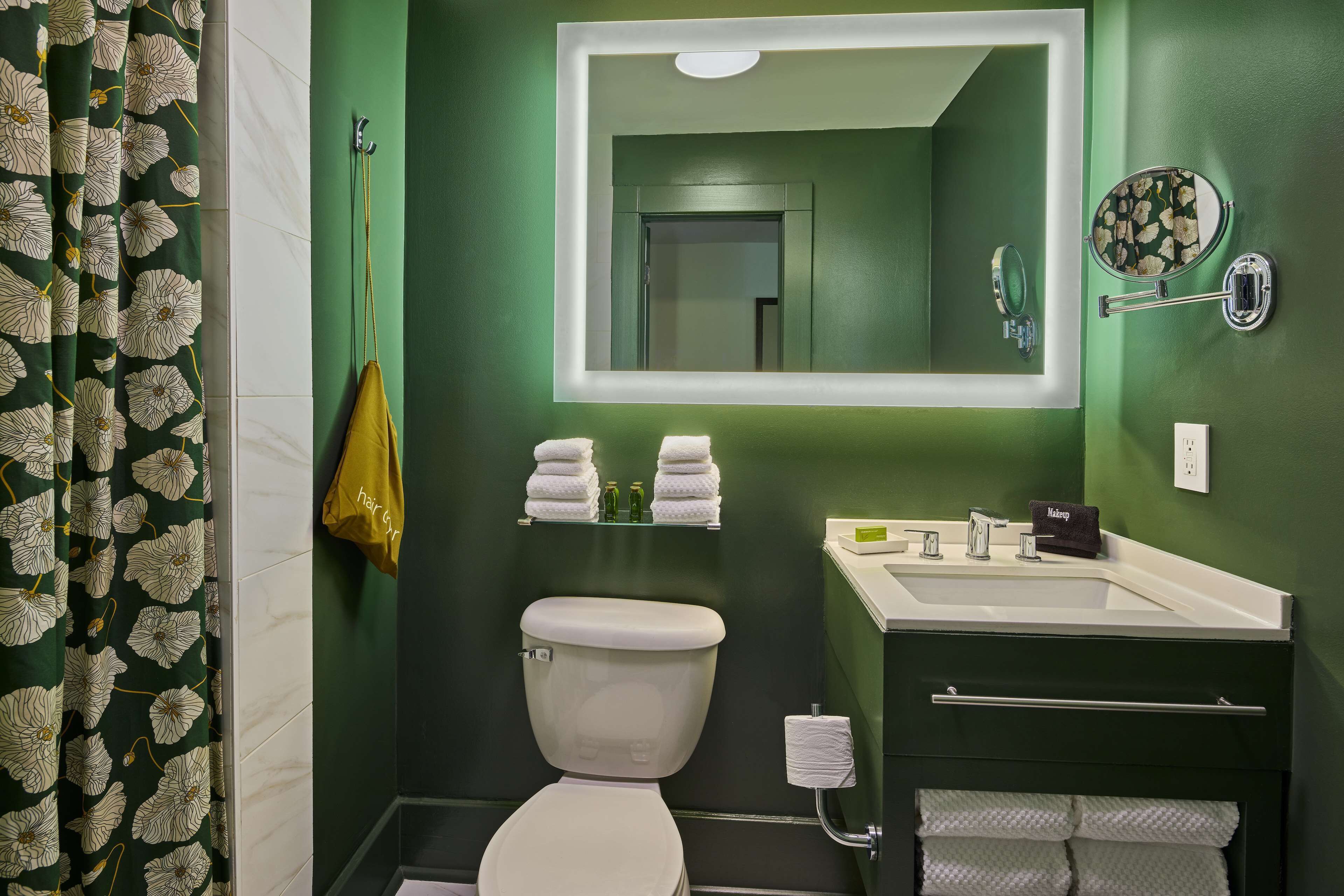 A bathroom with a toilet, sink, mirror, and towel racks.