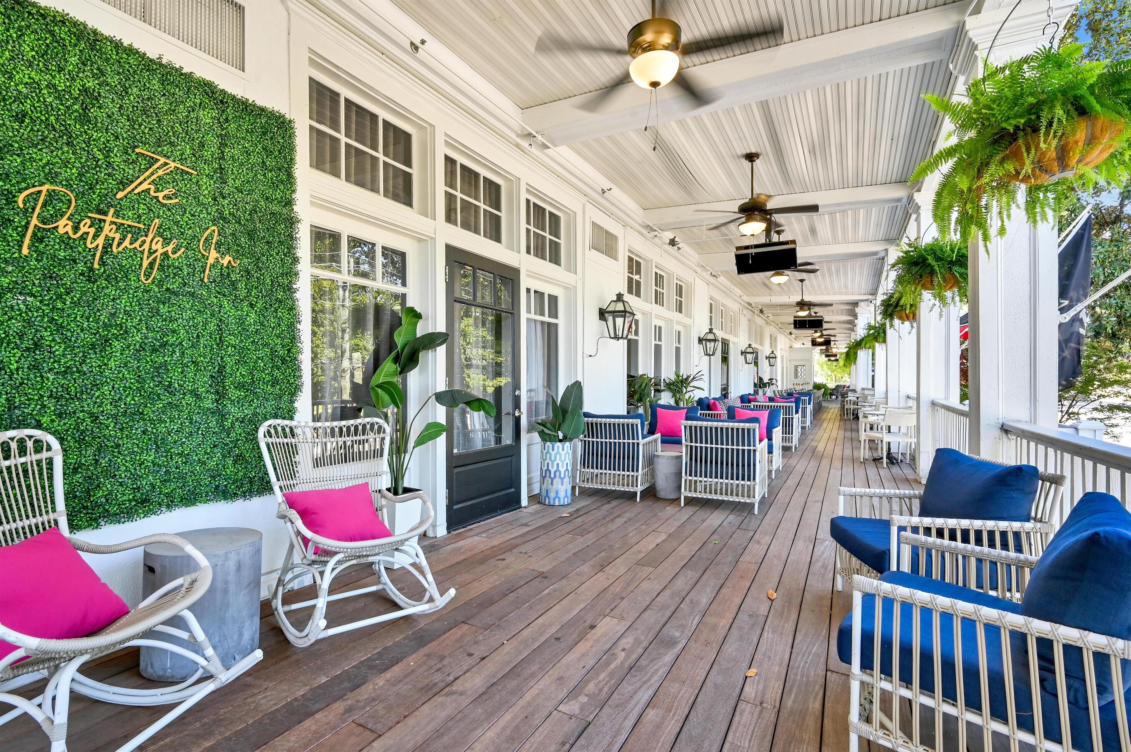 A covered outdoor area with white wicker furniture, green plants, and a sign reading "The Portugal Inn".