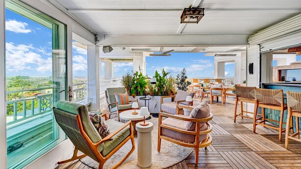 A spacious outdoor deck with wooden flooring, comfortable seating, and large windows offering a view of the city. - The Partridge Inn Augusta, Curio Collection by Hilton (Augusta)