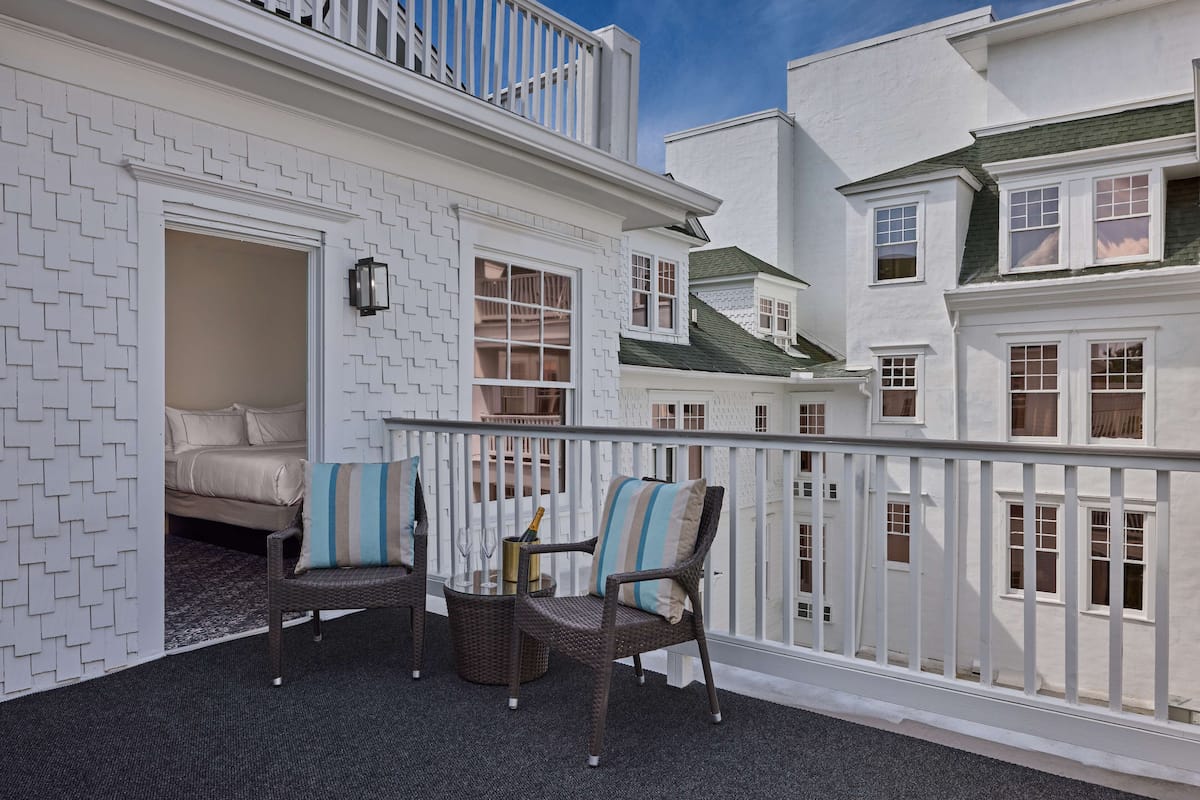 A balcony with wicker furniture and a bottle of champagne.