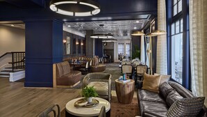 A spacious lobby with leather sofas, wooden tables, and a staircase. - The Partridge Inn Augusta, Curio Collection by Hilton (Augusta)