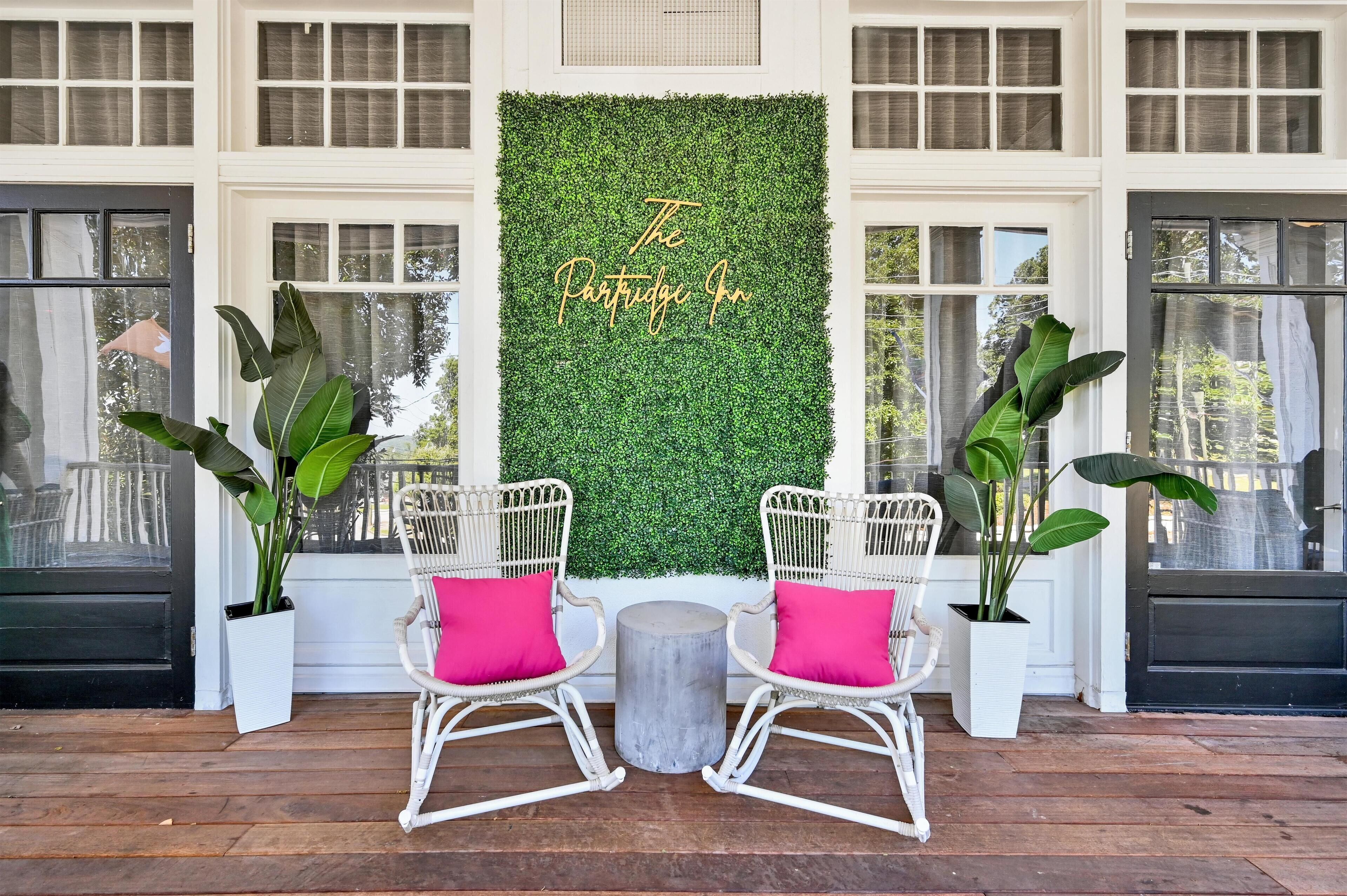 A porch with two rocking chairs, a round table, and a green wall with 'The Portuguese Inn' text.