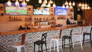 A bar area with hanging light fixtures, a television displaying a sports event, and a sign for ACCON Digital Network. - Quality Inn Miami South (Miami)