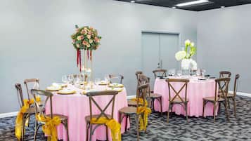 Uma sala de conferências com mesas redondas, cadeiras e arranjos florais.
