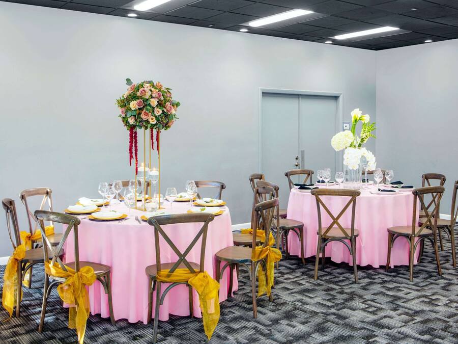 Uma sala de conferências com mesas redondas, cadeiras e arranjos florais.