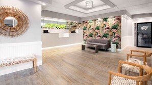 A reception area with a wooden bench, a sofa, and wicker chairs. - Quality Inn Miami South (Miami)