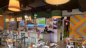 A bar area with a counter, hanging lights, and a neon sign. - Quality Inn Miami South (Miami)