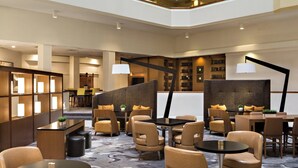 Un vestíbulo de hotel con zonas de estar, una recepción y una estantería.