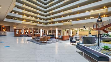 En rymlig entréhall med flera sittgrupper, en central trappa och en modern design.