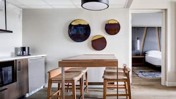 A modern kitchen with a wooden table and bar stools, a refrigerator, and decorative wall art.